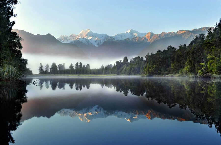 See mit Bäumen und Bergen im Hintergrund