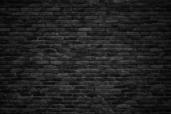 Schwarze Backsteinmauer mit einem weißen Fleck Schwarze Backsteinmauer mit einem weißen Fleck