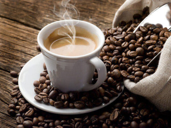 Tasse Kaffee auf einer Untertasse mit Kaffeebohnen Tasse Kaffee auf einer Untertasse mit Kaffeebohnen