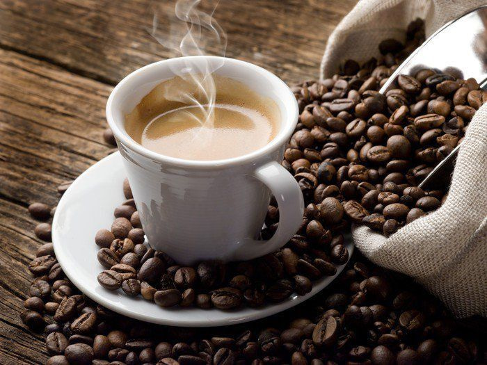 Tasse Kaffee auf einer Untertasse mit Kaffeebohnen Tasse Kaffee auf einer Untertasse mit Kaffeebohnen