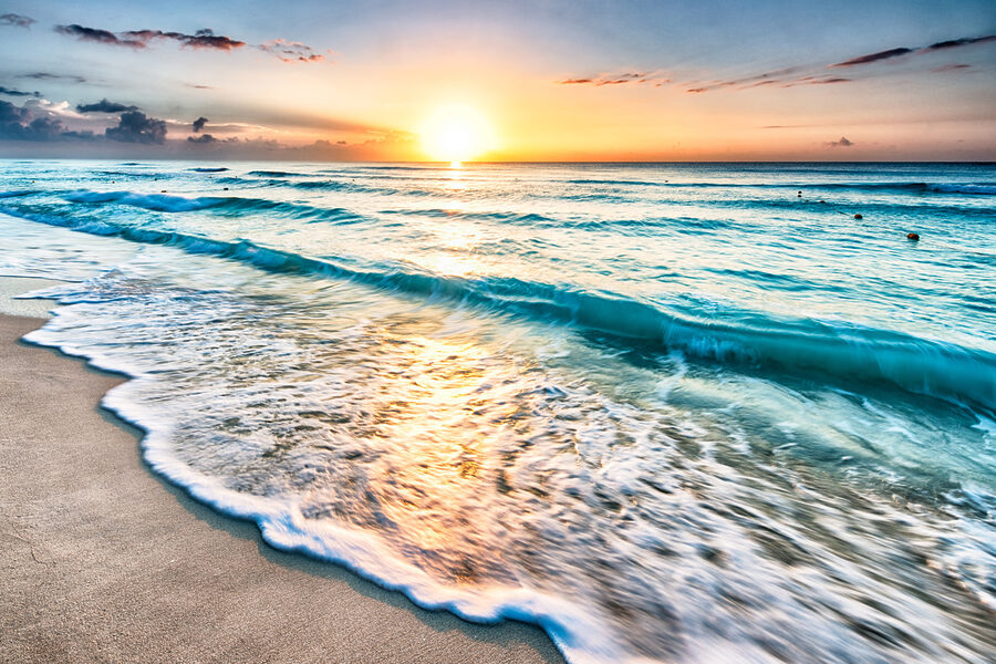 Ein Strand mit Wellen und einem Sonnenuntergang