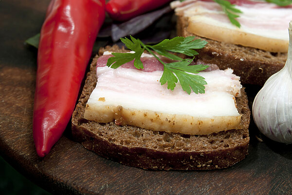 Ein Stück Brot mit Speck und Petersilie darauf Ein Stück Brot mit Speck und Petersilie darauf