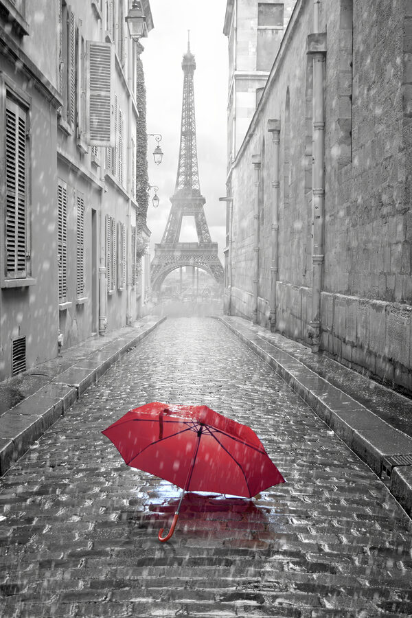Ein roter Regenschirm in einer Straße mit einem Turm im Hintergrund Ein roter Regenschirm in einer Straße mit einem Turm im Hintergrund