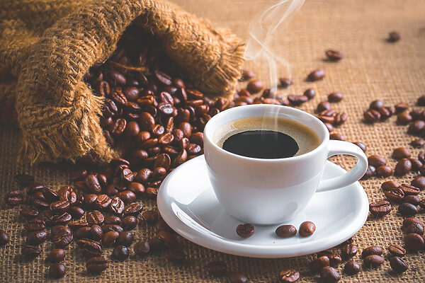 Eine Tasse Kaffee und eine Tüte mit Kaffeebohnen Eine Tasse Kaffee und eine Tüte mit Kaffeebohnen