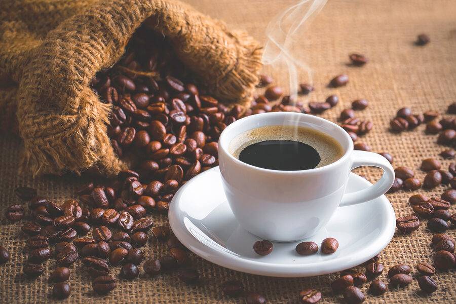 Eine Tasse Kaffee und eine Tüte mit Kaffeebohnen Eine Tasse Kaffee und eine Tüte mit Kaffeebohnen