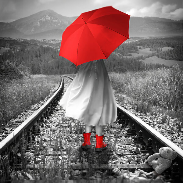 Eine Person mit einem roten Regenschirm auf einer Bahnstrecke Eine Person mit einem roten Regenschirm auf einer Bahnstrecke