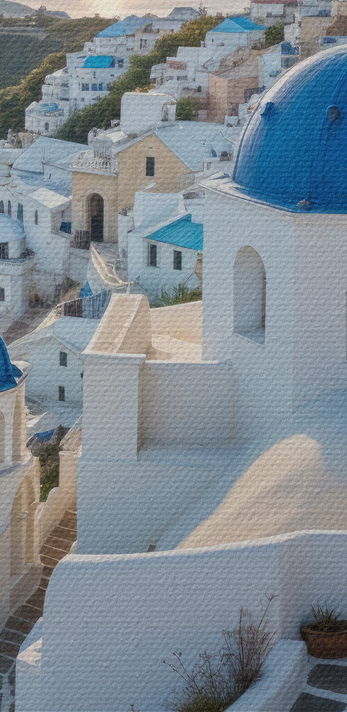 White buildings with blue domes on a hill with a body of water in the background