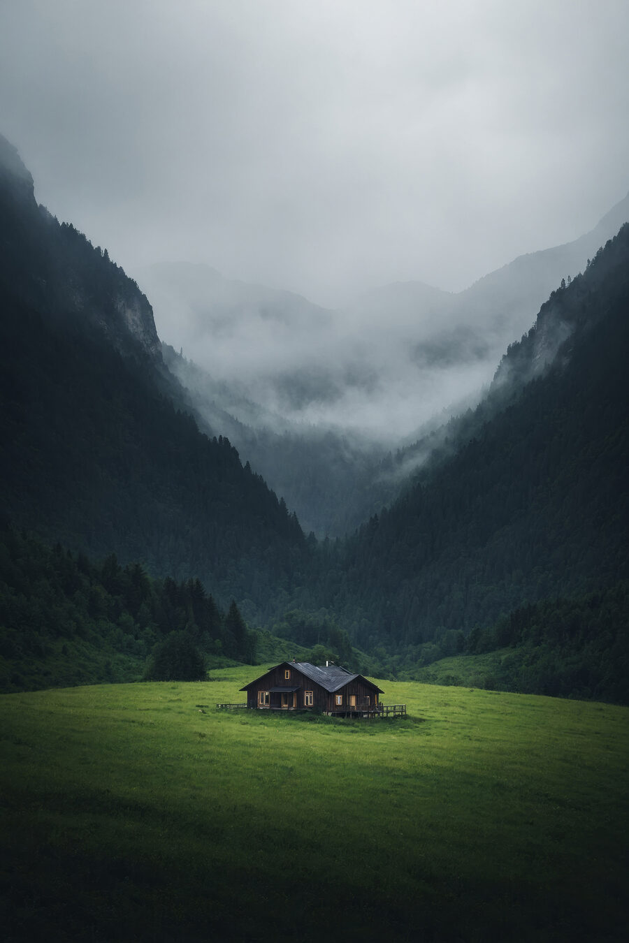 Haus auf einem Feld mit Bergen im Hintergrund Haus auf einem Feld mit Bergen im Hintergrund