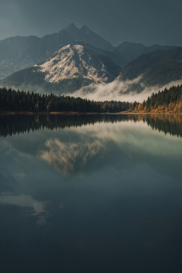 See mit Bäumen und Bergen im Hintergrund See mit Bäumen und Bergen im Hintergrund