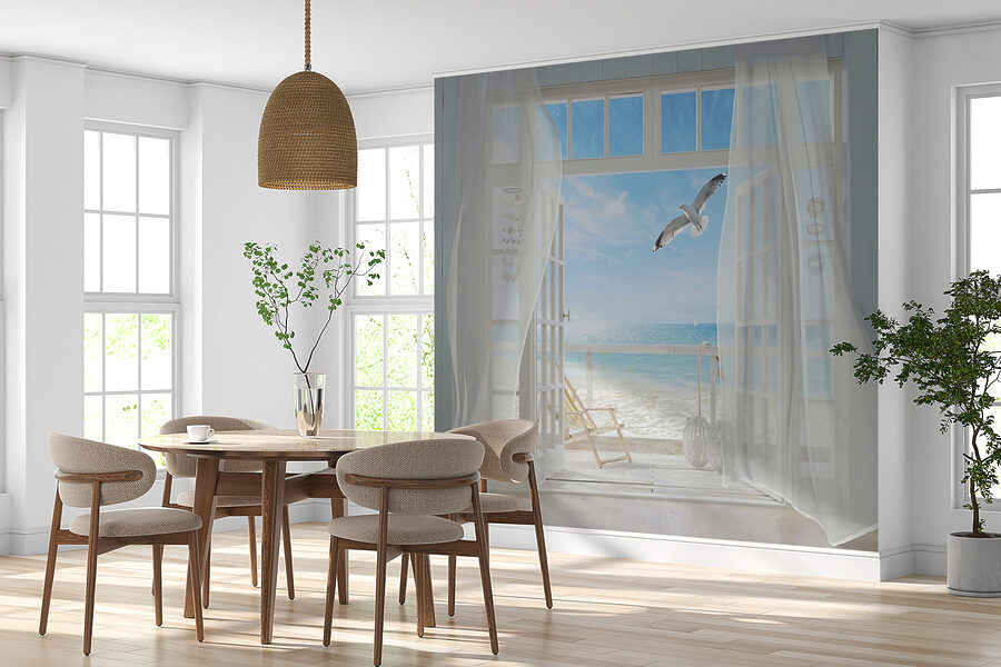 Blick auf einen Strand aus einem Zimmer mit einem Vogel, der über ihn fliegt