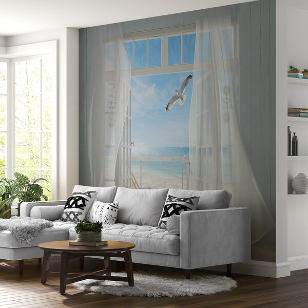 Blick auf einen Strand aus einem Zimmer mit einem Vogel, der über ihn fliegt Blick auf einen Strand aus einem Zimmer mit einem Vogel, der über ihn fliegt